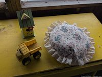 Pillow, toy dump truck and birdhouse grouped together