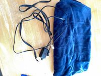 Folded navy electric throw blanket with attached black controller and power cord on wooden surface