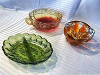 Three decorative glass bowls in green, amber/red and amber/clear