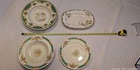 Four dinnerware pieces with measuring tape for scale