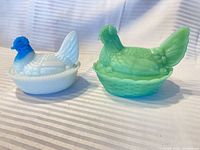 Two hen on nest covered dishes, white/blue and green, side by side with lids on