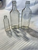 Three clear embossed bottles standing side by side