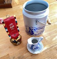 Group shot showing cowbell, creamer with saucer, and metal milk can