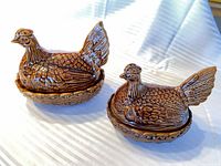 Two brown glazed hen-on-nest covered dishes side by side