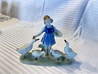 Front view of porcelain figurine girl with four geese
