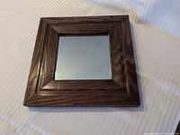 Front view of square mirror with dark brown wood frame