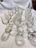 Twelve clear cut-crystal wine glasses arranged on table showing mixed patterns and stem styles
