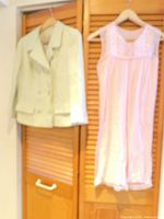Mint green jacket and pink slip dress hanging on wooden louvered doors