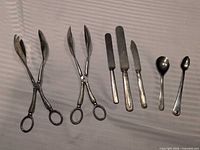 Full set laid out: two tongs, three knives/spreaders, two spoons