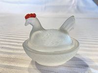 Side view of frosted glass hen on nest showing red comb and overall form