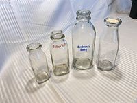 Front view of all four glass milk bottles showing branding and sizes