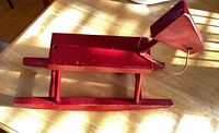 Full view of red wooden rocking horse on tabletop