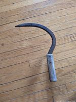 Full view of sickle showing blade curve and wood handle