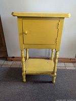Full view of yellow wooden nightstand with cabinet door and lower shelf