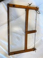 Full view of wooden frame saw lying flat, showing complete frame, blade, and tension rope