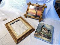 Group shot of all three items: empty wood frame with mat, rope-accent framed sunset print, unframed city canvas painting