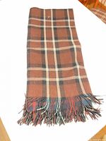Blanket folded showing brown, navy and cream plaid and fringe