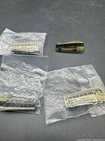 Four bus-shaped brooches, three bagged, one loose