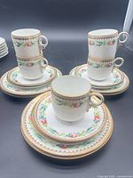 Group of cups stacked on saucers with dessert plates, showing full set