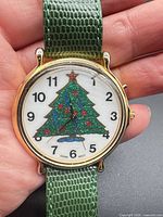 Front view of watch showing Christmas tree dial, gold case, green strap
