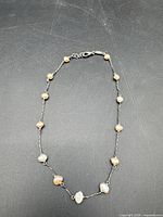 Full view of necklace laid flat showing pearls and chain