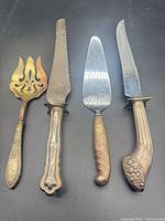 Four antique sterling silver serving utensils laid out side by side