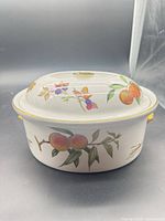 Side view of covered bowl displaying fruit pattern and gold trim