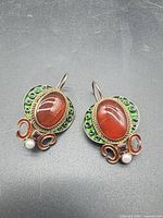 Front view of both earrings showing carnelian, green enamel, garnet and pearl
