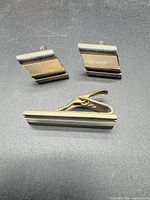 Front view of cufflinks and tie clip showing design and materials
