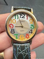 Close view of watch face showing brand, multicolored numerals and gold-tone case