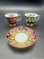Front view of two teacups and one saucer showing patterns and gold trim
