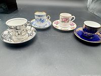 Four demitasse cup and saucer sets on tabletop