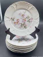Stack of six matching Limoges dessert plates showing pattern and rim detail