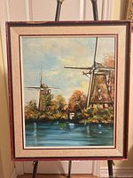 Full view of framed signed oil painting with windmills and water