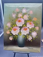 Full view of the signed floral oil painting on canvas displayed on easel