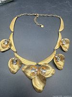 Full view of gold-tone floral statement necklace showing overall design and extender chain