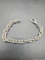 Full view of sterling silver oval-link chain bracelet on black background