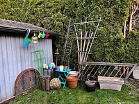Overall view of lot beside shed showing trellises, bench, table, pots, hanging planters, bird feeder