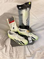 Overall lot showing Adidas cleats with box, sealed Adidas shin guards, and Lotto socks