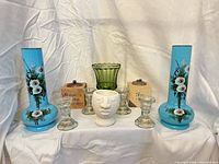 Front view displaying all items: blue vases, green vase, face planter, clear candlesticks, wood holders