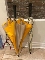 Pair of closed umbrellas leaning against wall