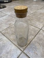 Clear glass carafe with cork stopper standing on tile floor