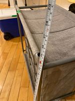 Overall view of closet organizer showing fabric drawers, metal frame and measurement tape for height