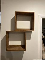 Full view of two joined wooden cube shelves on wall