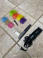 Clipper with power cord, colored guards, comb, brush laid out on tile floor