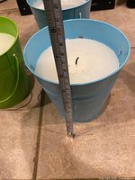 Side view showing height of blue bucket candle with tape at roughly 7 in