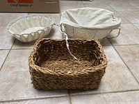 Front view of all three baskets: natural woven rectangular, white wicker round, white wire oval with liner