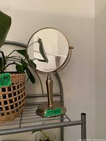 Round pedestal vanity mirror with plant for scale