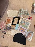 All items laid out on carpet showing range of books, glassware, textiles, mirror, hook, craft notions