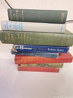 Stack of seven vintage hardcovers showing spines and edges